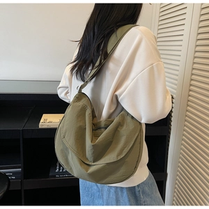 Detail of army green nylon crescent bag showing soft folds and wide shoulder strap