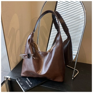 Detail of dark brown leather texture and small logo on a large vintage hobo shoulder bag