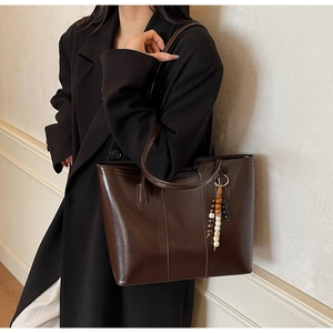 Dettaglio di una borsa tote grande in pelle cerata marrone con finitura vintage lucida