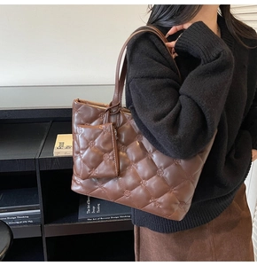 Detail of brown quilted tote bag with diamond stitching and matching pouch charm