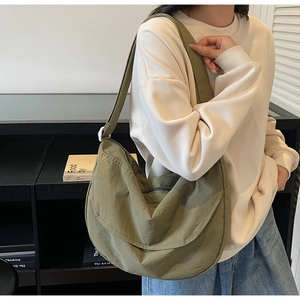 Close-up of green nylon crescent hobo bag with wide shoulder strap and metal zipper