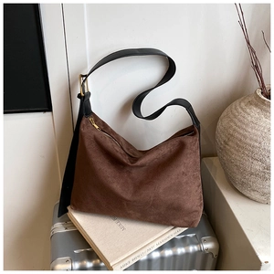 Détail d'un sac hobo en daim marron avec bandoulière en cuir noir et boucles dorées