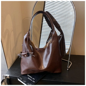 Detail of dark brown leather tote bag with wide shoulder strap and sunglasses holder charm