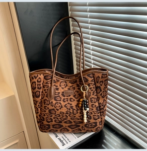 Detailed view of leopard print tote bag with brown leather handles and beaded tassel