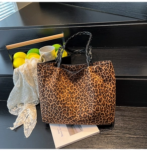 Detail of leopard print tote bag with black woven rope handles on stone stairs