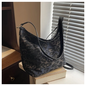 Detail of large leopard print bucket bag featuring premium metal buckle and leather straps