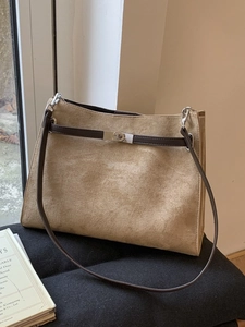 Minimalist khaki suede tote bag with brown straps and silver clasp in elegant scene
