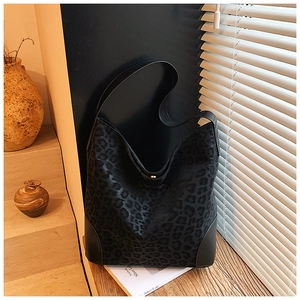 Detailed view of leopard print texture and leather base of a large tote bag on a table