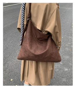 Detailed outdoor shot of a large brown leopard print hobo bag with wide shoulder strap