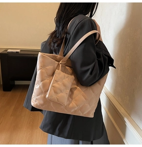 Detail of beige quilted tote bag with floral stitching and matching small pouch
