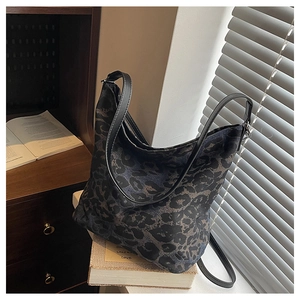 Close-up of leopard print canvas tote bag with black leather shoulder strap detail