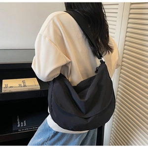 Side view of large black nylon crescent bag with adjustable wide strap on model