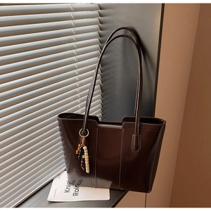 Dettaglio della borsa shopper marrone scuro con finitura lucida e nappa di perline