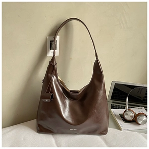 Detail of vintage brown leather tote bag with white logo in a minimalist office setting