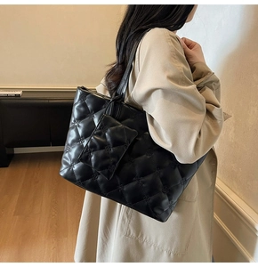 Detail of black quilted leather tote bag with floral embroidery and small zip pouch