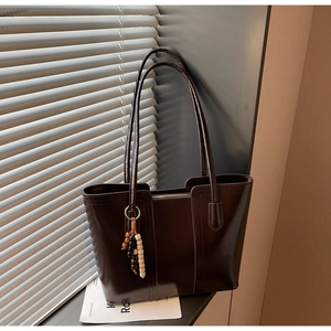 Borsa tote marrone scuro in ecopelle con ciondolo di perline sulla tracolla lunga