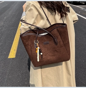 Close-up of deep brown suede tote bag featuring bohemian wooden beads and a sleek leather strap