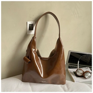 Detail of dark brown patent leather Hobo bag with cylinder charm and brand logo