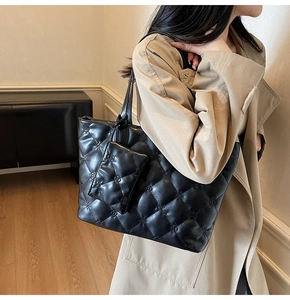 Detail of black quilted tote bag with matching coin purse and floral embossing
