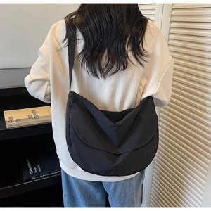 Detailed back view of a large black nylon crescent crossbody bag worn by a model