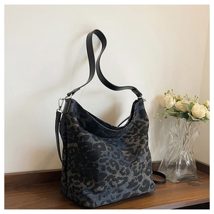 Detail of blue and black leopard print hobo bag on a rustic wooden table surface