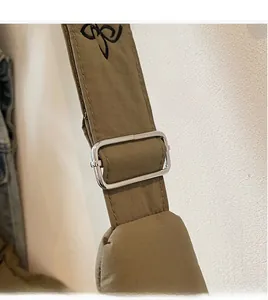 Detail of adjustable nylon shoulder strap with silver buckle on olive green canvas bag