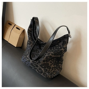 Top view of a large leopard print canvas tote bag with black leather straps on a sofa