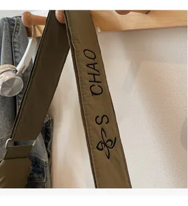 Detail of olive green canvas strap with black embroidery on a casual shoulder bag