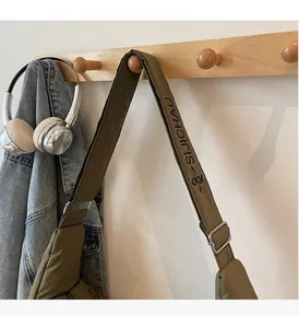 Detail of adjustable padded strap with SUICHAO logo on an olive green canvas crossbody bag