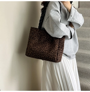 Detail view of large leopard print tote bag with woven handles on a model in minimalist setting