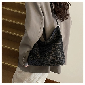 Close-up of leopard print canvas hobo bag with sleek black leather strap on a model