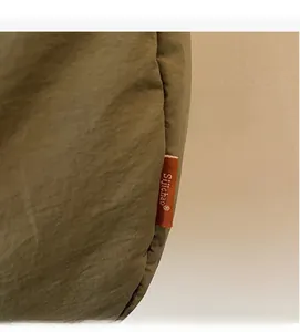 Detailed close-up of olive green canvas fabric with branded orange woven label detail