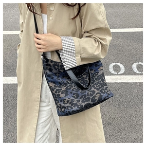 Detail of leopard print tote bag with blue and brown patterns and black leather straps
