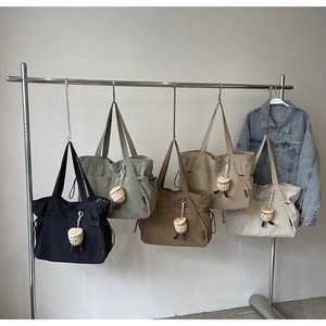 Vue détaillée de grands sacs cabas en nylon en cinq couleurs avec breloques cupcake