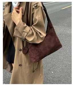 Detail view of dark brown suede tote bag styled with a classic khaki trench coat