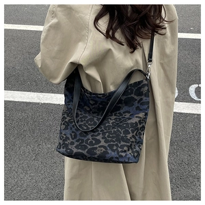 Detail of leopard print canvas tote bag featuring premium leather handles and metal hardware