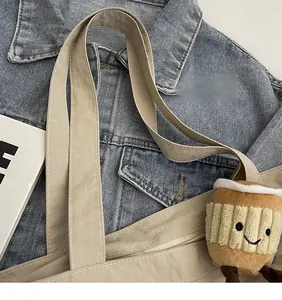 Détail du sac fourre-tout beige avec bandoulière lisse et charmant pendentif café en peluche