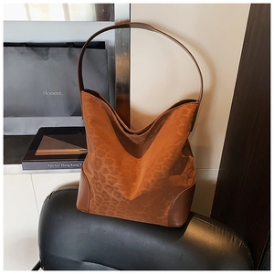 Detail of leopard print tote bag with brown leather trim and handles on dark leather