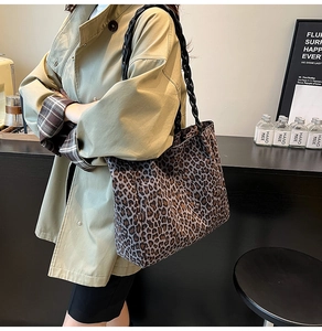 Detail view of large leopard print tote bag featuring black braided shoulder strap and canvas