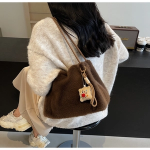 Dettaglio della borsa tote in peluche marrone scuro con ciondolo carino e tracolla in pelle