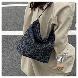 Close-up of leopard print canvas tote bag with black shoulder straps and spacious interior