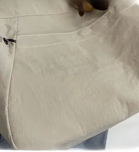 Gros plan du sac beige montrant la texture plissée du tissu et le cordon de serrage noir