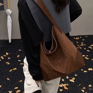 Detailed view of large leopard print tote bag featuring leather straps and sturdy base