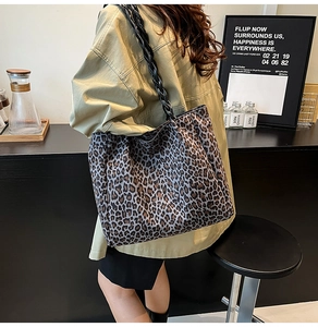 Close-up of a leopard print suede tote bag with black woven rope handles on a model