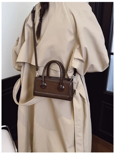 Detailed view of brown vintage handbag with dual ball ornaments and crossbody strap