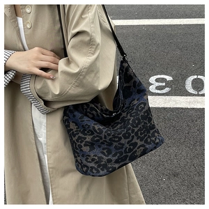 Close-up of leopard print canvas hobo bag with black leather strap on street