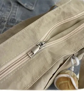 Détail d'une fermeture éclair en métal et d'un charm en peluche sur un sac en nylon