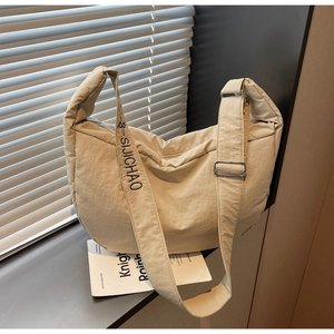 Detail view of beige nylon crossbody bag with adjustable wide strap and branded lettering
