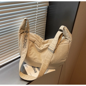 Detail of beige nylon cloud bag showing padded texture and branded wide shoulder strap