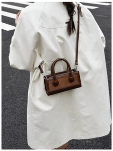 Detail of deep brown vintage handbag with synthetic leather texture on a city street
